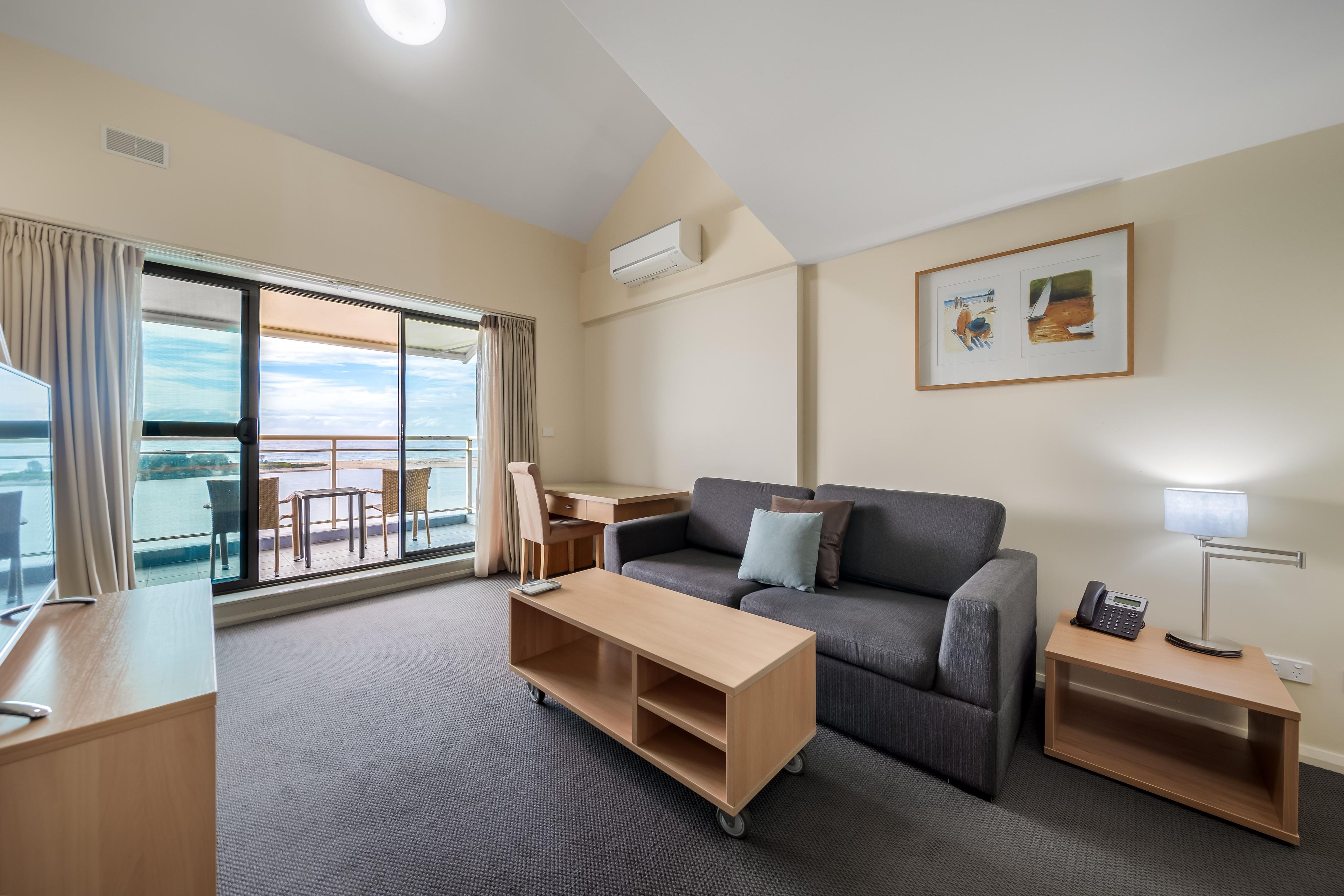 Et moderne hotelværelse med balkon, sofa, skrivebord og lille bord.