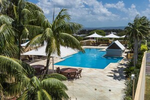 Una piscina rodeada de palmeras y mobiliario exterior.