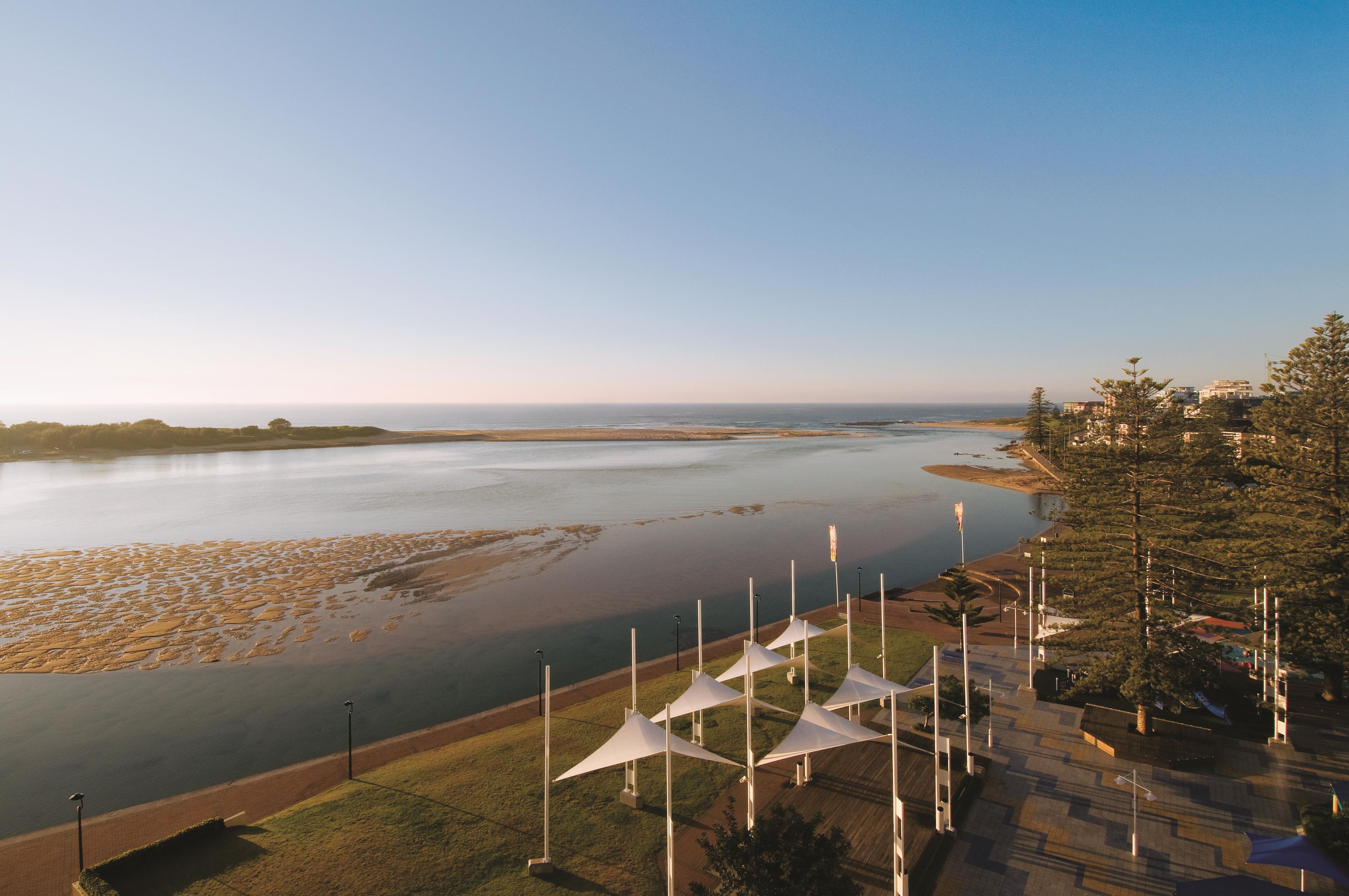 A coastal view with a river, grassy areas, and white structures.