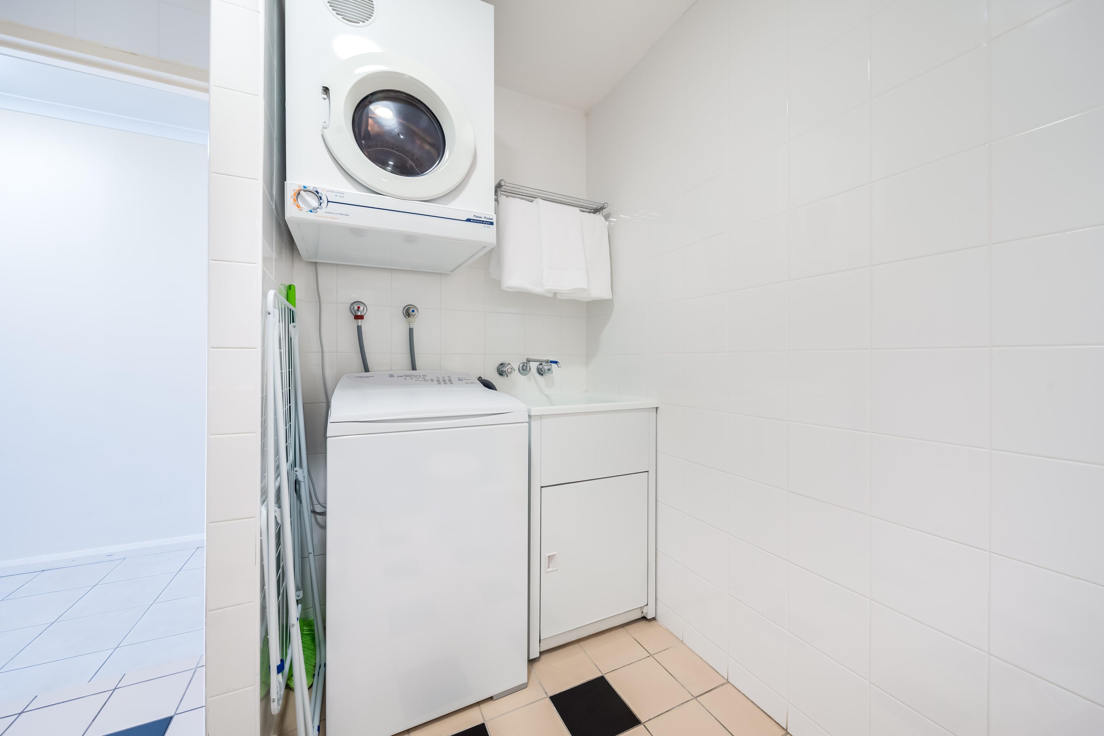 A compact laundry room with a washing machine, dryer, and ironing station.