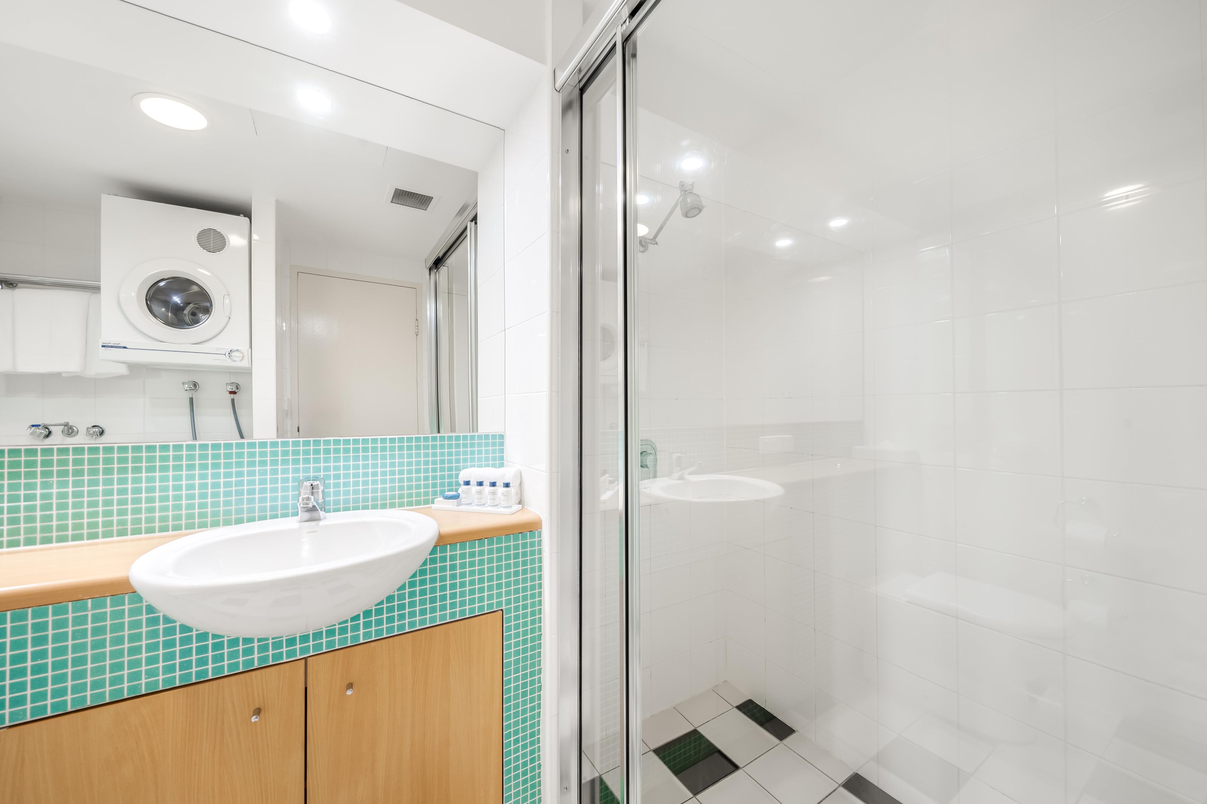 Une salle de bain moderne avec une douche à parois de verre, un lavabo doté d’un plan de travail en bois et un miroir au-dessus du lavabo.