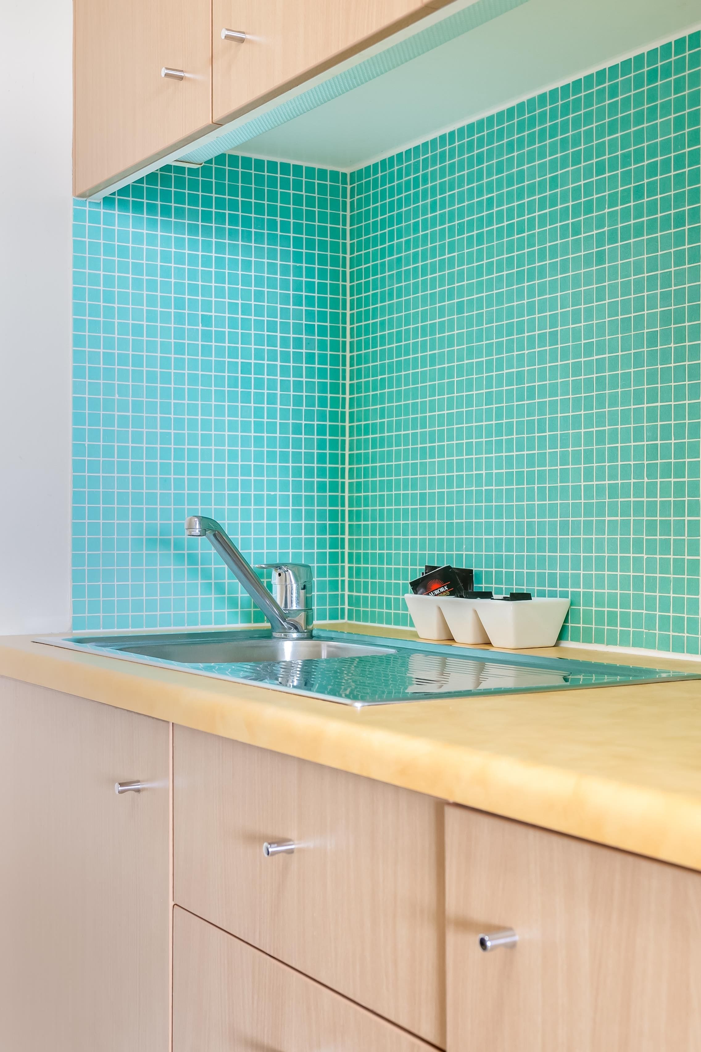 A kitchen with a sink, cabinets, and a tiled backsplash.