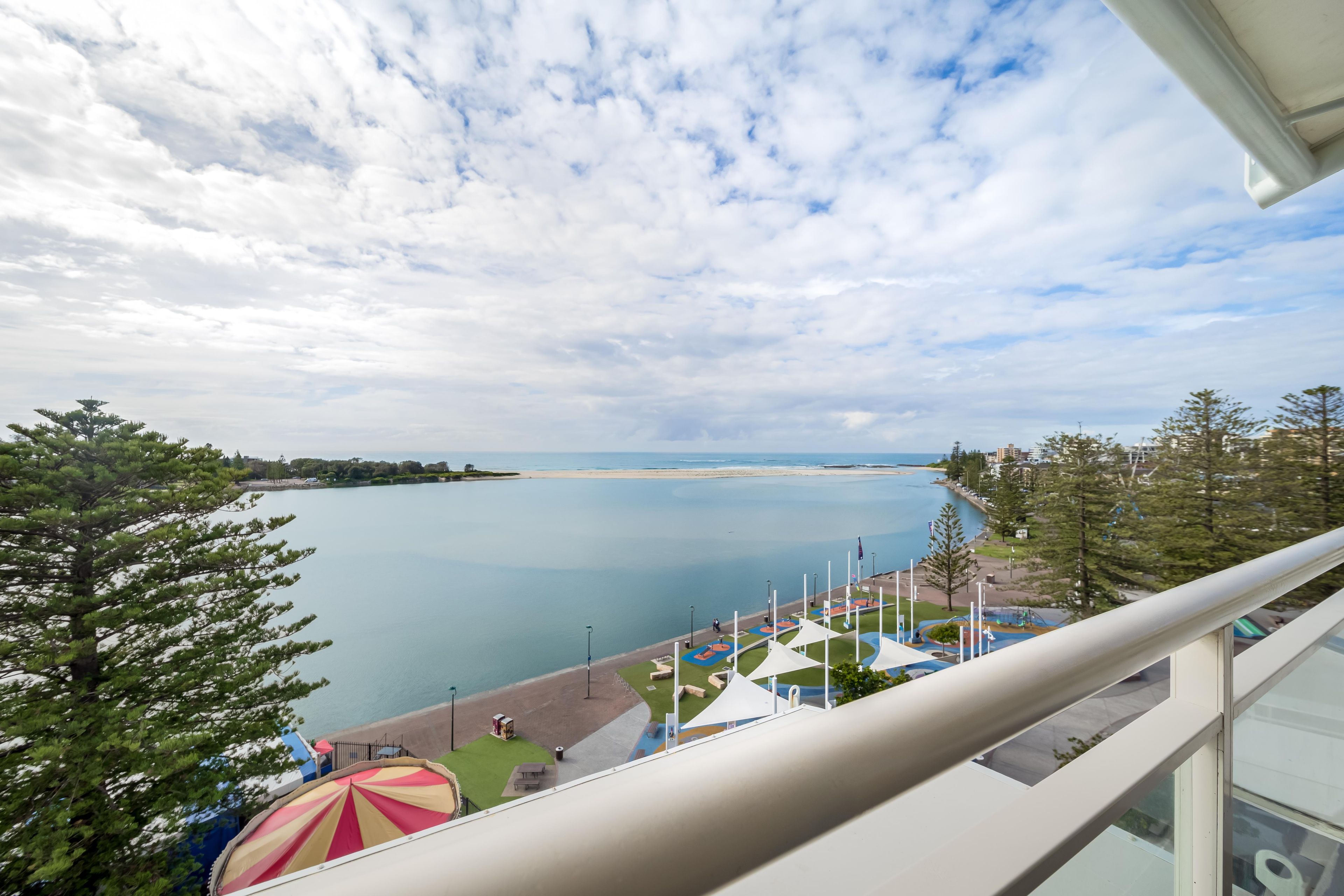 A view of a waterfront with a beach, a playground, and a clear sky.