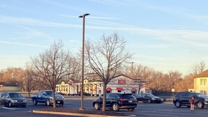 A parking lot with several cars, a stop sign, and a building with a sign that reads "Travelodge by Wyndham."