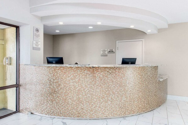 A reception desk with a mosaic tile design, a glass door entrance, and a ceiling with recessed lighting. - Clarion Inn & Suites Kissimmee-Lake Buena Vista South (Kissimmee)