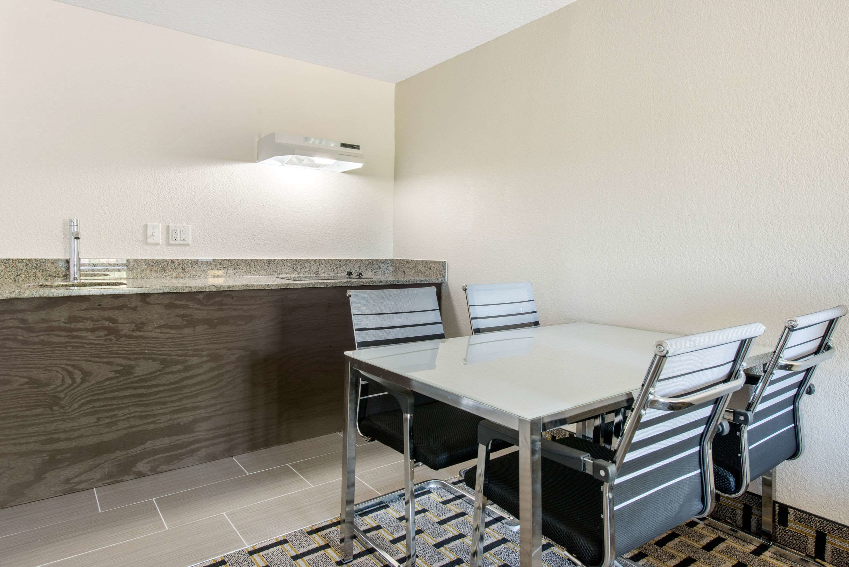A compact kitchen with a granite countertop, a built-in stove, and a dining area with a table and four chairs.