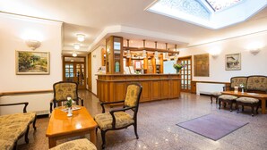 A lobby with a reception desk, seating area, and a skylight. - Hotel Geneva (Sofia)