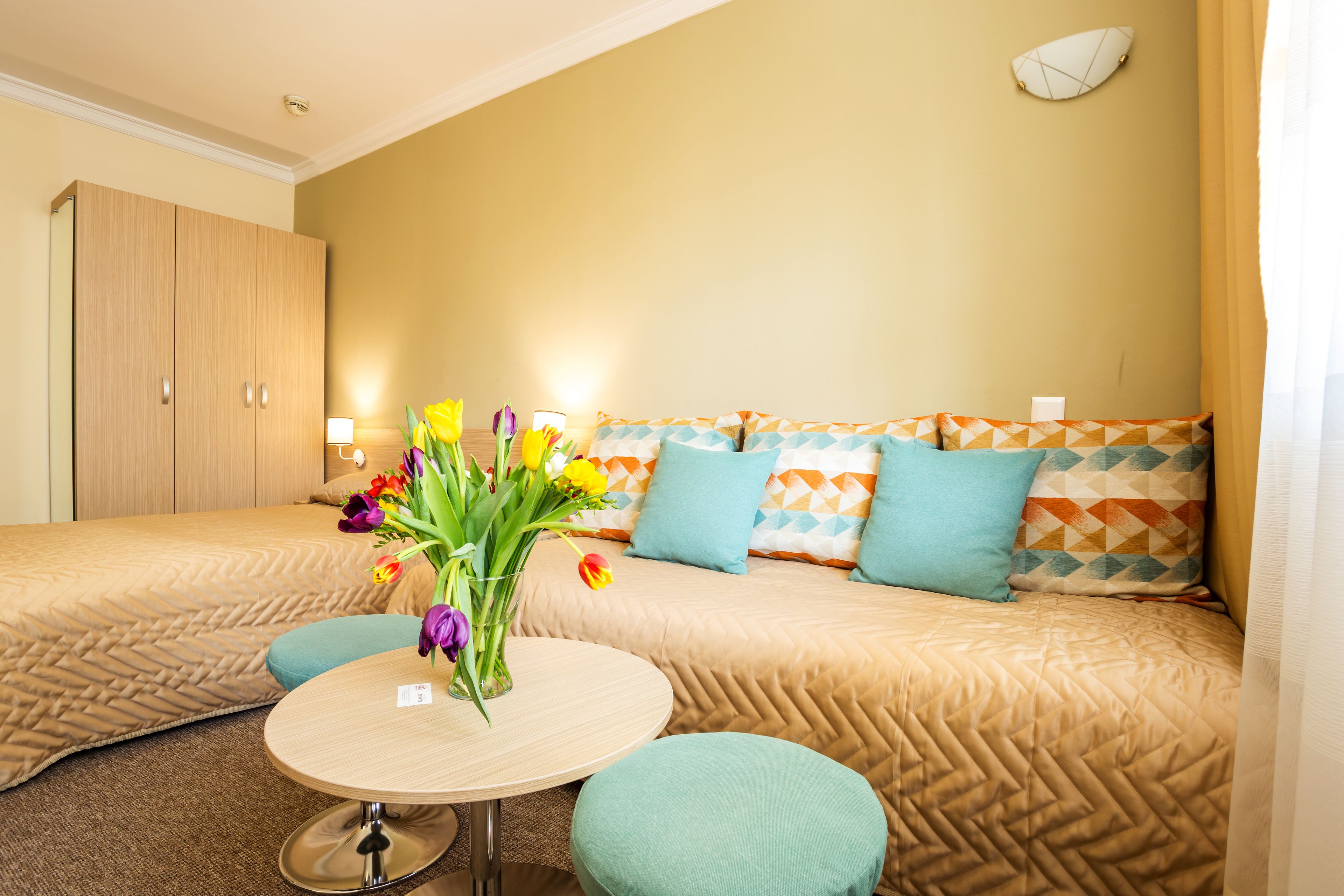 Habitació d'hotel amb llit, taula rodona i un ram de flors.