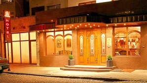 A hotel with a classic facade, large wooden doors, and a neon sign. - Hotel Geneva (Sofia)
