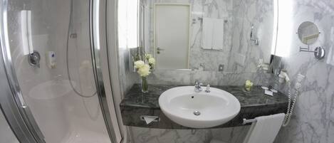 A modern bathroom with a glass-enclosed shower, a marble sink, and a large mirror.