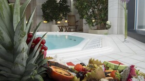 A spa area with a hot tub, a dining table, and a variety of fruits and vegetables.