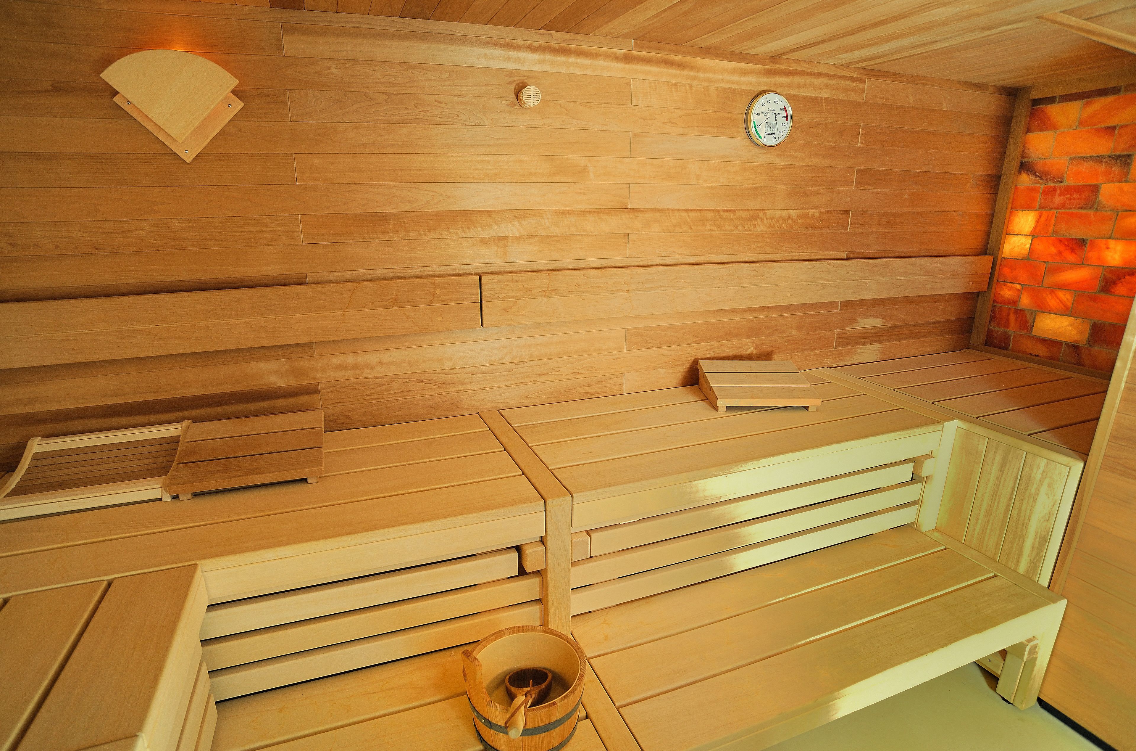 A sauna with wooden benches and a wall-mounted clock.