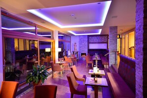 Relax in our lounge area, featuring sofas, chairs, and tables for individual and group gatherings, with a fireplace and large windows.