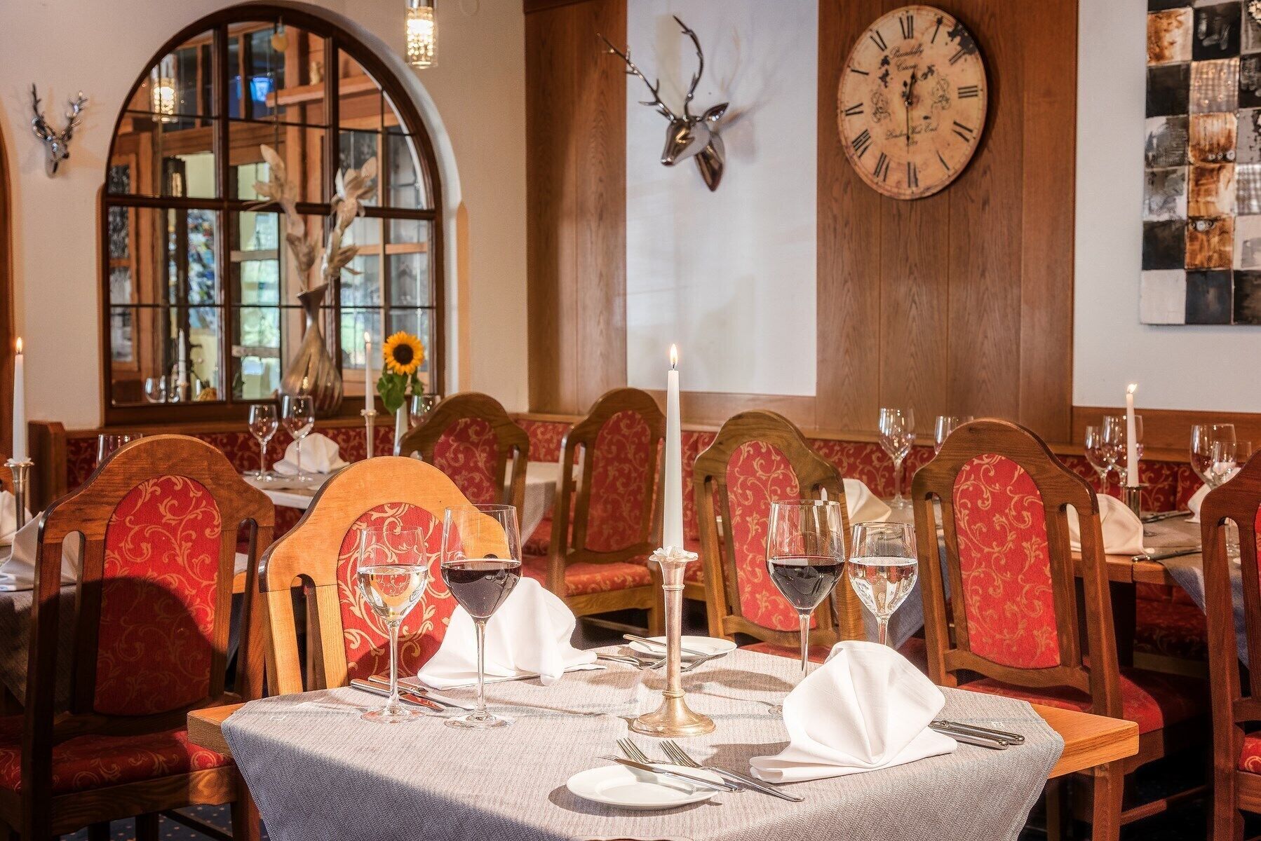 Un restaurante con mesas de madera, sillas tapizadas en rojo y un gran reloj de pared.