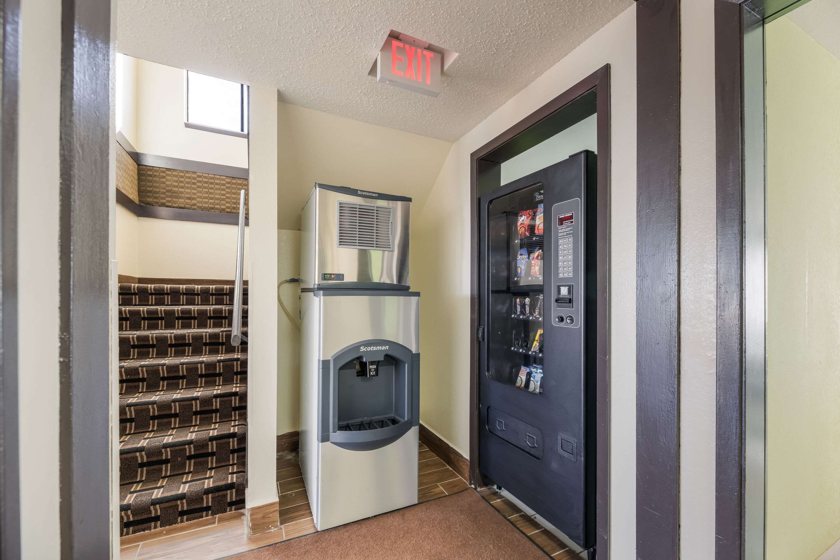 A hallway with a water dispenser, a vending machine, and a staircase.