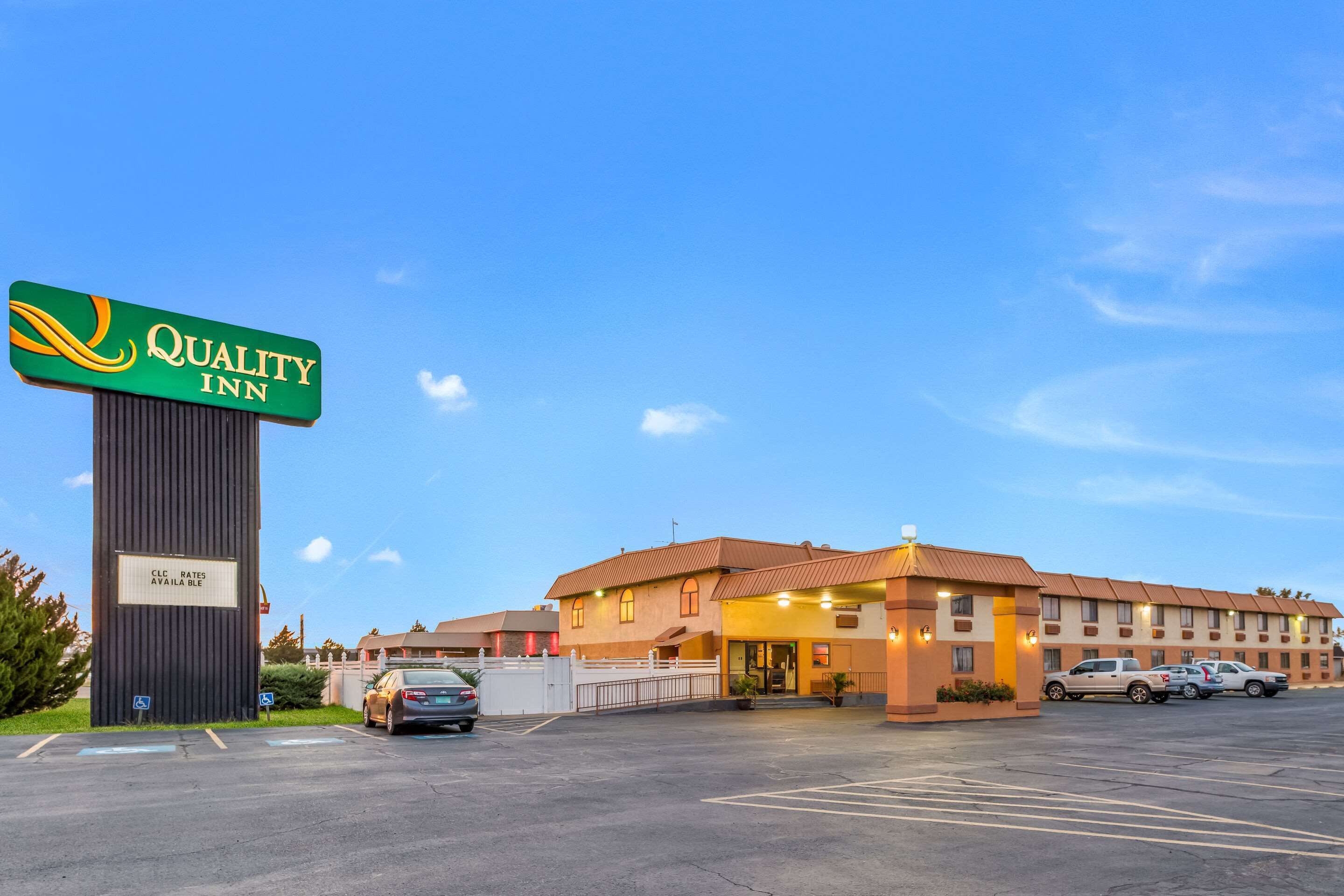 Ett Quality Inn-hotell med en stor skylt, en parkeringsplats och en byggnad med flera rum.