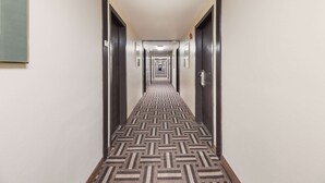 A hotel hallway with a patterned carpet, dark doors, and a light-colored wall. - Quality Inn Clovis (Clovis)