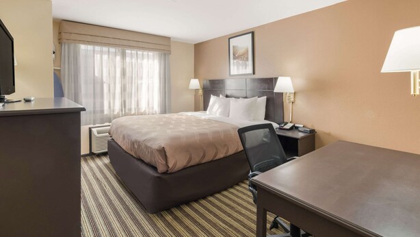 A hotel room with a large bed, a desk, a chair, and a television. - Quality Inn Clovis (Clovis)