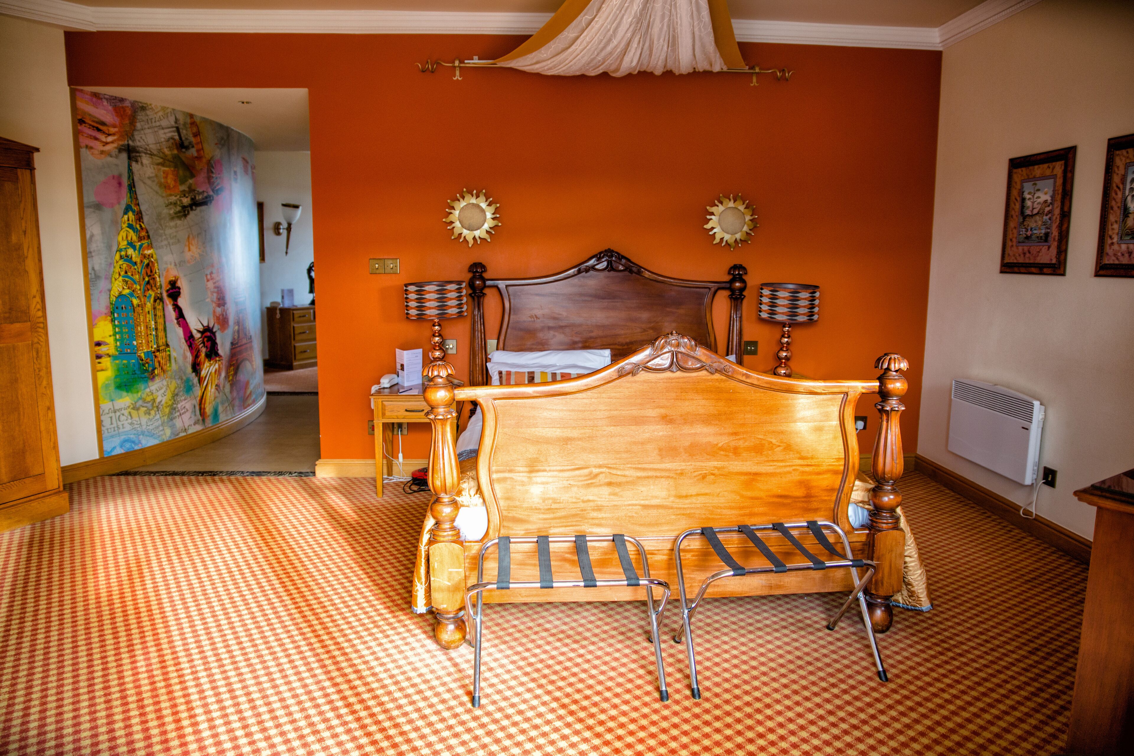 Una camera da letto con un letto in legno, due lampade a parete, un quadro grande appeso al muro e un pavimento a scacchi.