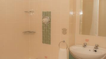 Une salle de bain avec une baignoire, un lavabo et un miroir. On y trouve également un porte-serviettes et une poubelle.