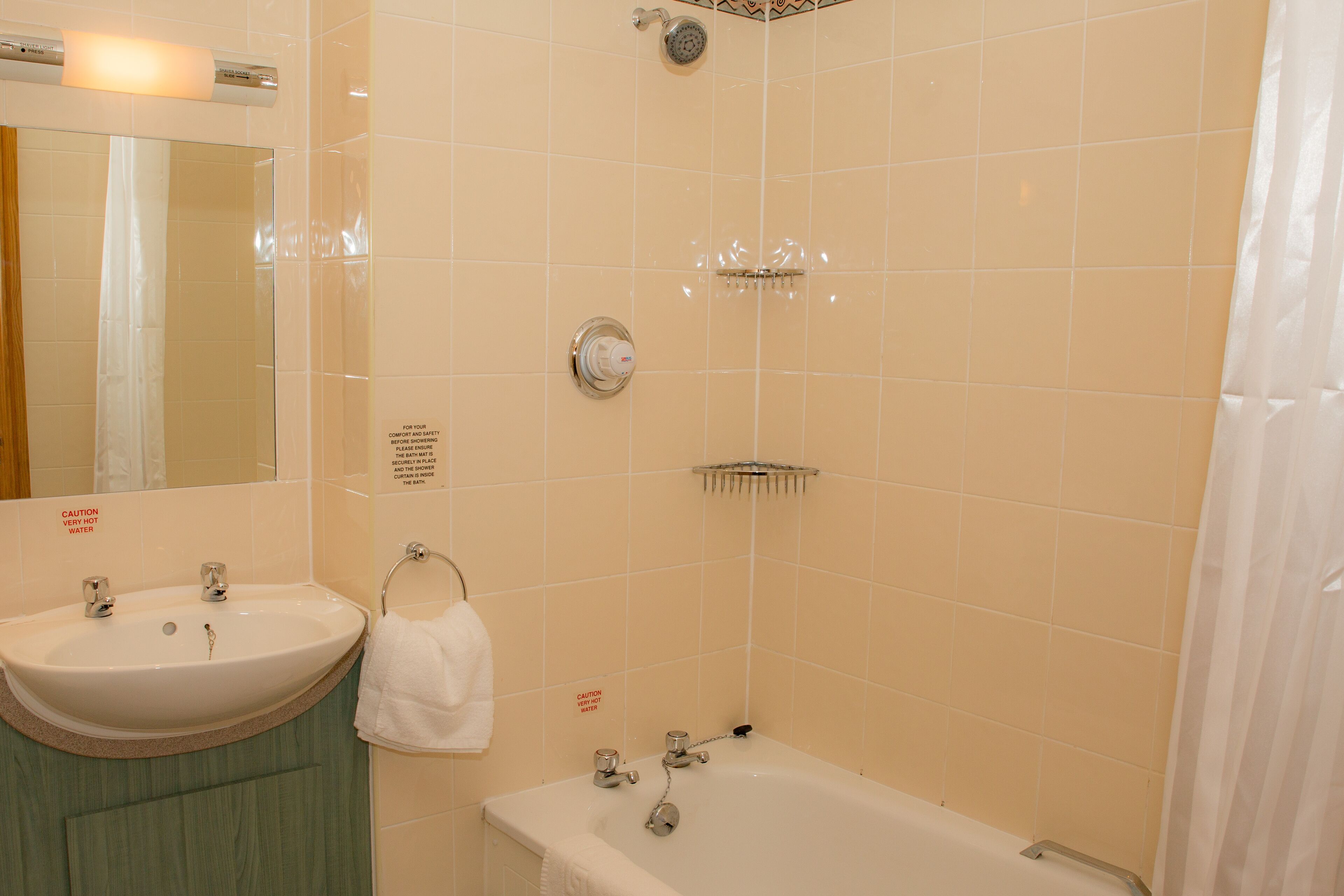 Een badkamer met een wastafel, spiegel en bad.