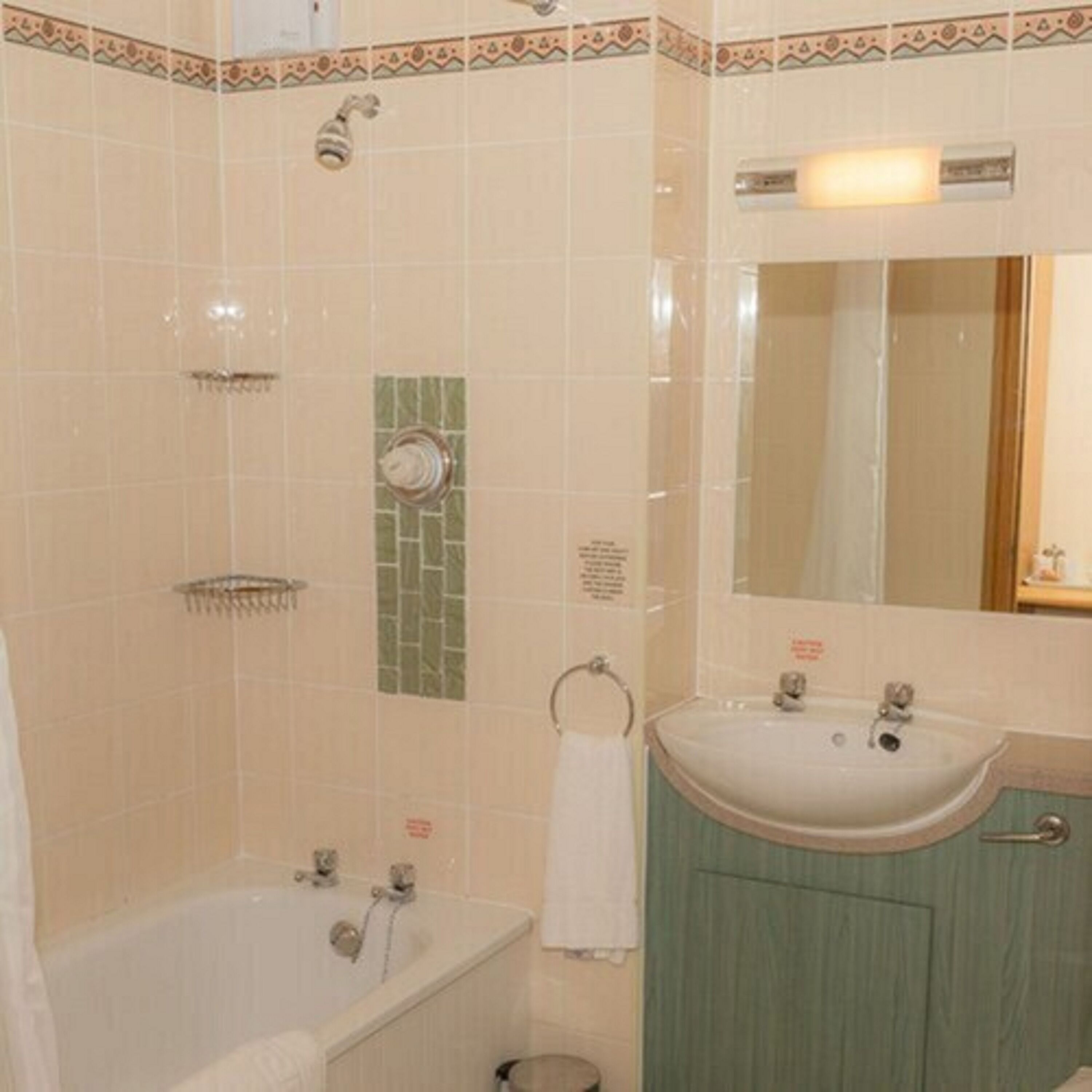 Un baño con bañera, lavamanos, espejo y ducha.