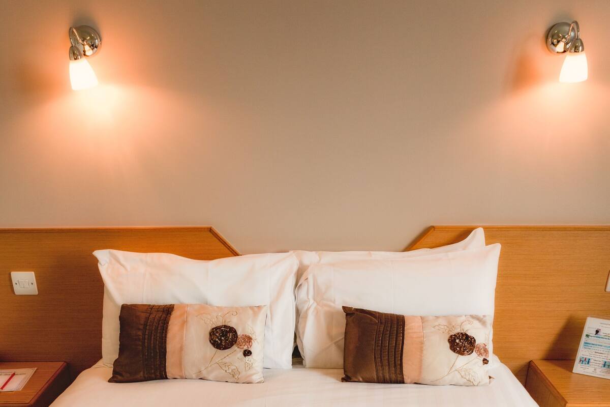 Ein ordentlich bezogenes Bett mit einer gesteppten Decke und zwei Zierkissen.