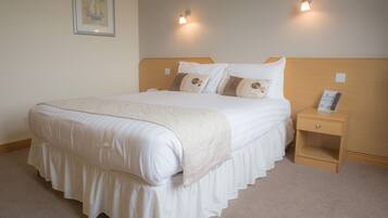 A neatly made bed with a wooden headboard, two bedside tables, and a wall-mounted light fixture.