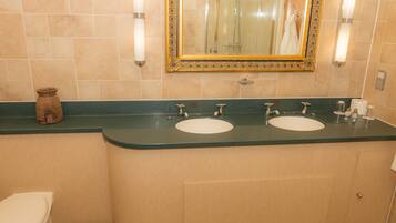 Un baño con dos lavamanos, un inodoro y un espejo con marco decorativo.
