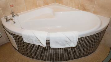 A bathtub with two towels, a faucet, and a tiled wall.