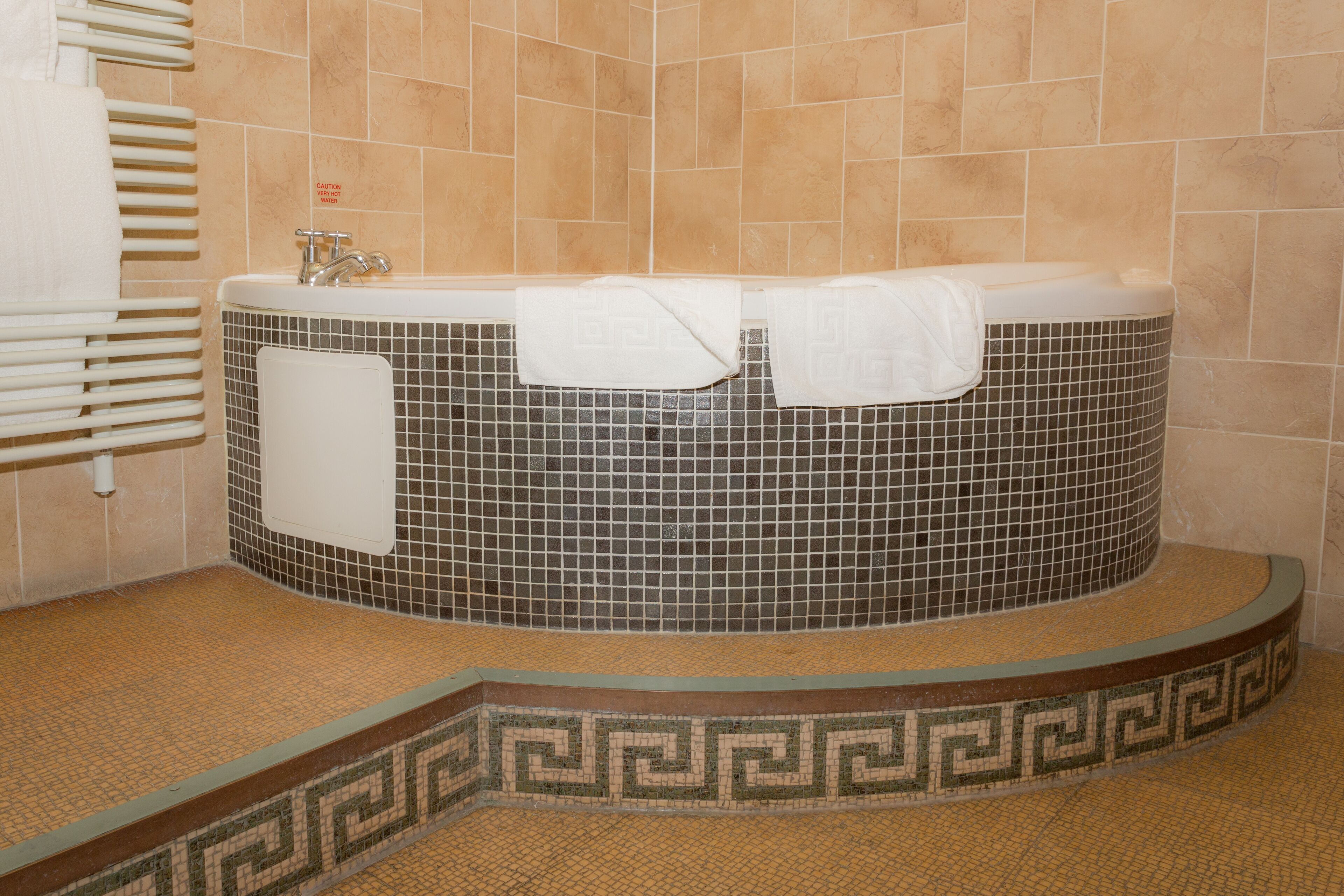 Une salle de bain avec une baignoire sur pieds, un porte-serviettes et un panneau d’avertissement.