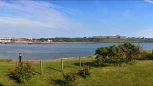 A grassy area with a view of a river and a distant building. - Little Haven Hotel On The Beach (South Shields)