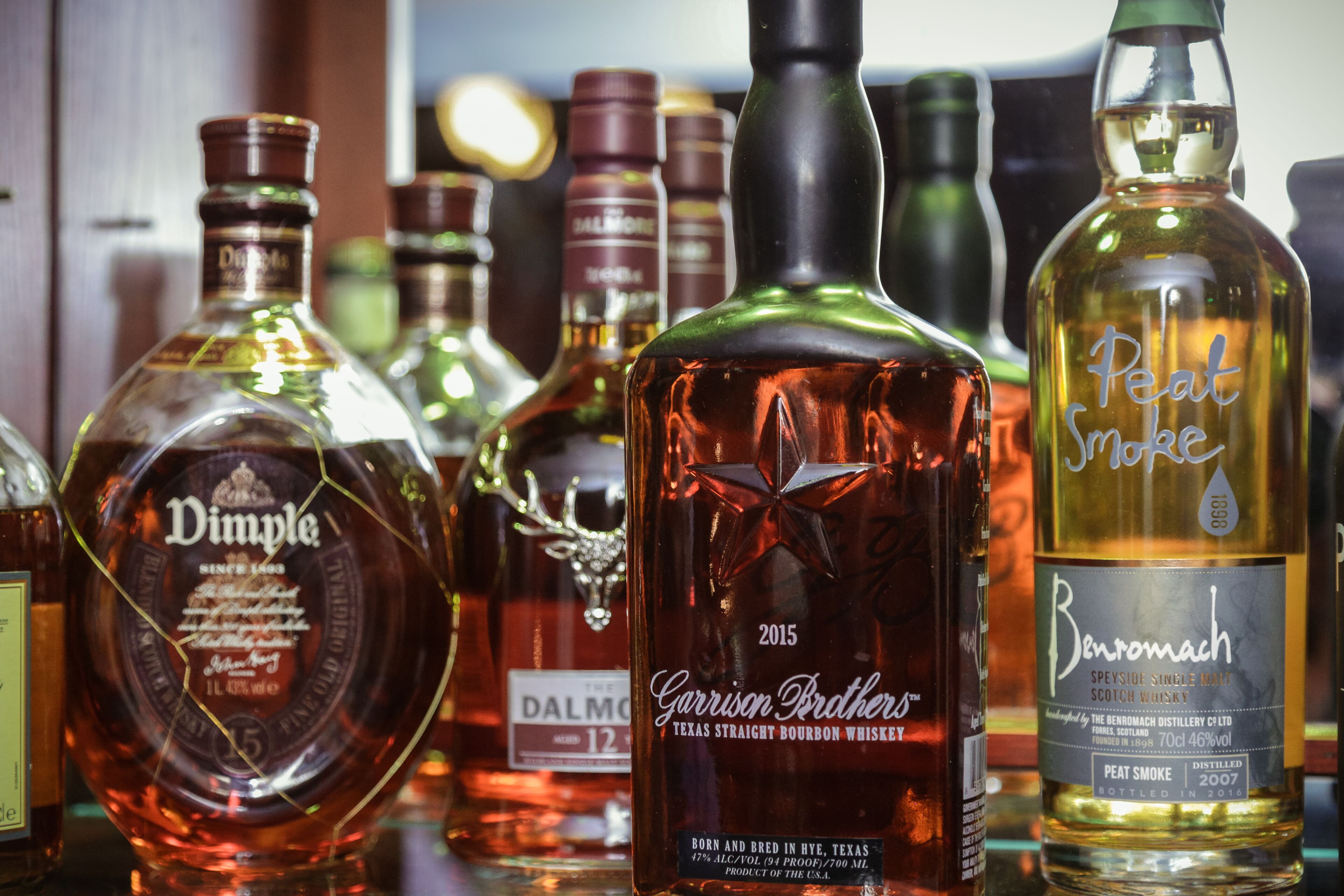 A variety of whiskey bottles on a shelf.