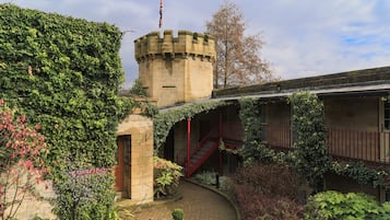 Una estructura que parece un castillo, con muros cubiertos de hiedra, una escalera roja y un letrero de recepción.