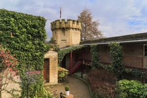 Una estructura que parece un castillo, con muros cubiertos de hiedra, una escalera roja y un letrero de recepción.