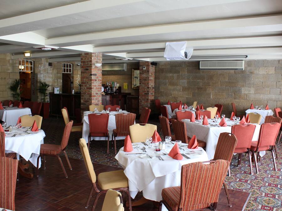 Ein Restaurant mit mehreren Essplätzen, das gestreifte Stühle und rote Servietten zeigt.