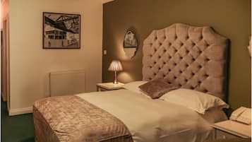 A hotel room with a large bed, a bedside lamp, a radiator, and a framed picture on the wall.
