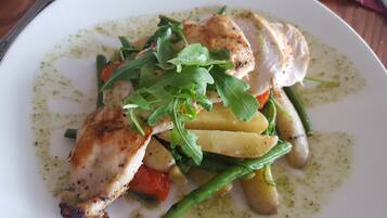 A plate of food with chicken, vegetables, and a green sauce.