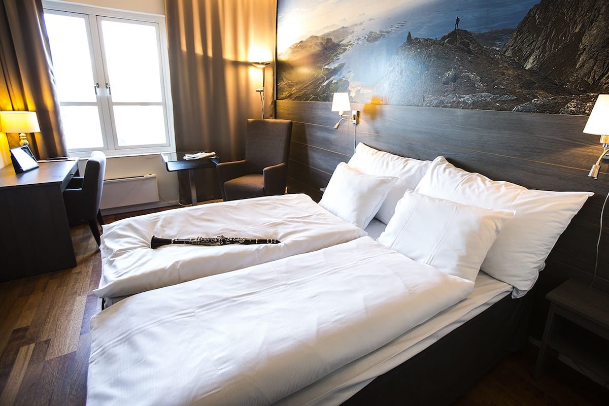 Habitación de hotel con una cama grande, un escritorio, una silla y vistas a un paisaje montañoso.