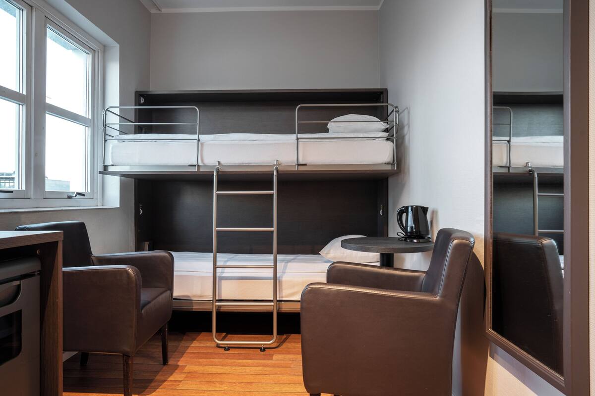 Habitación con literas, escritorio, sillas y cafetera.