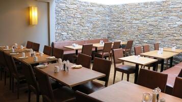 A restaurant with multiple tables and booths, stone walls, and a ceiling light fixture.