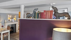 Zona de recepción con chimenea, espejo y estantería con libros.