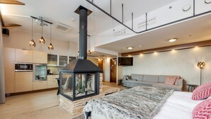 Un interior modern amb un llit gran, una llar de foc, una cuina i una zona de estar.