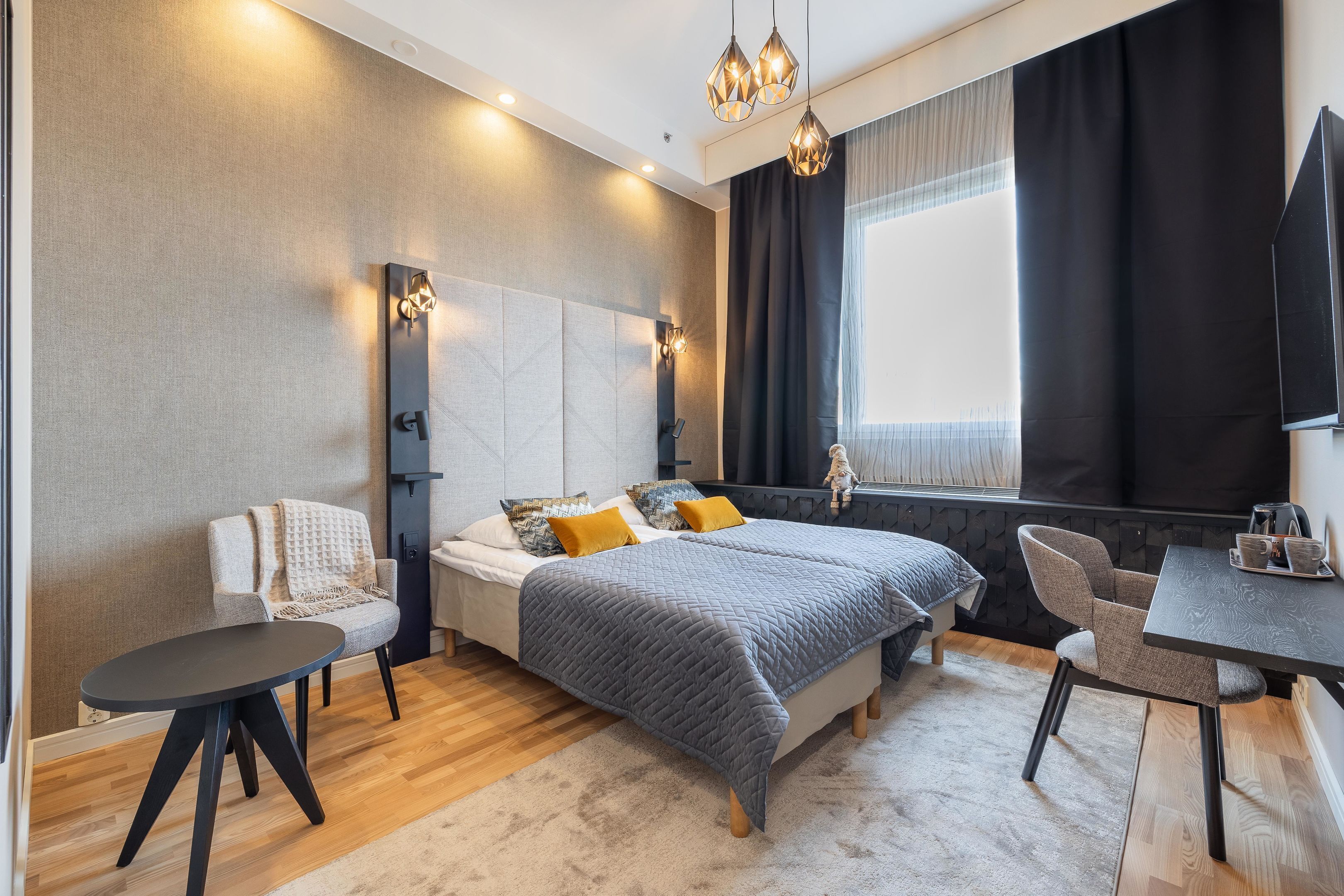 A modern bedroom with a bed, bedside tables, a chair, a desk, and a large window with curtains.