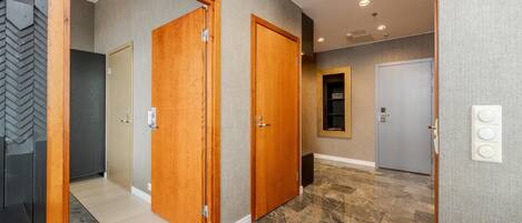 A hallway with wooden doors, a carpeted area, and a tiled floor.
