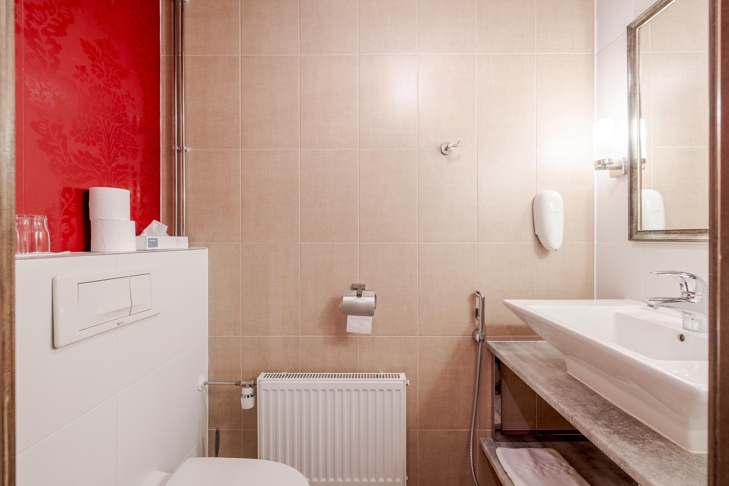 Un baño con lavamanos blanco, espejo, inodoro y zona de ducha.