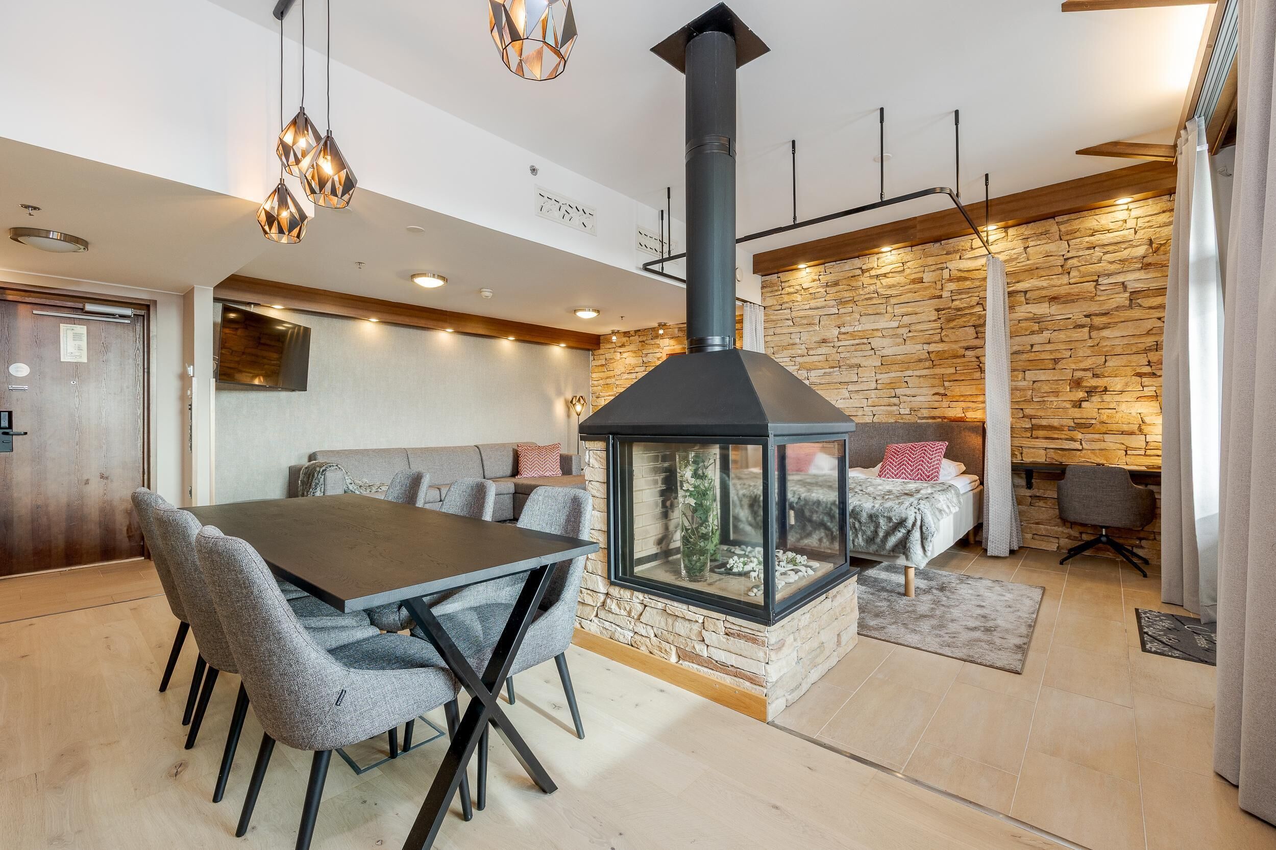 A modern interior with a dining area, a fireplace, and a stone wall.