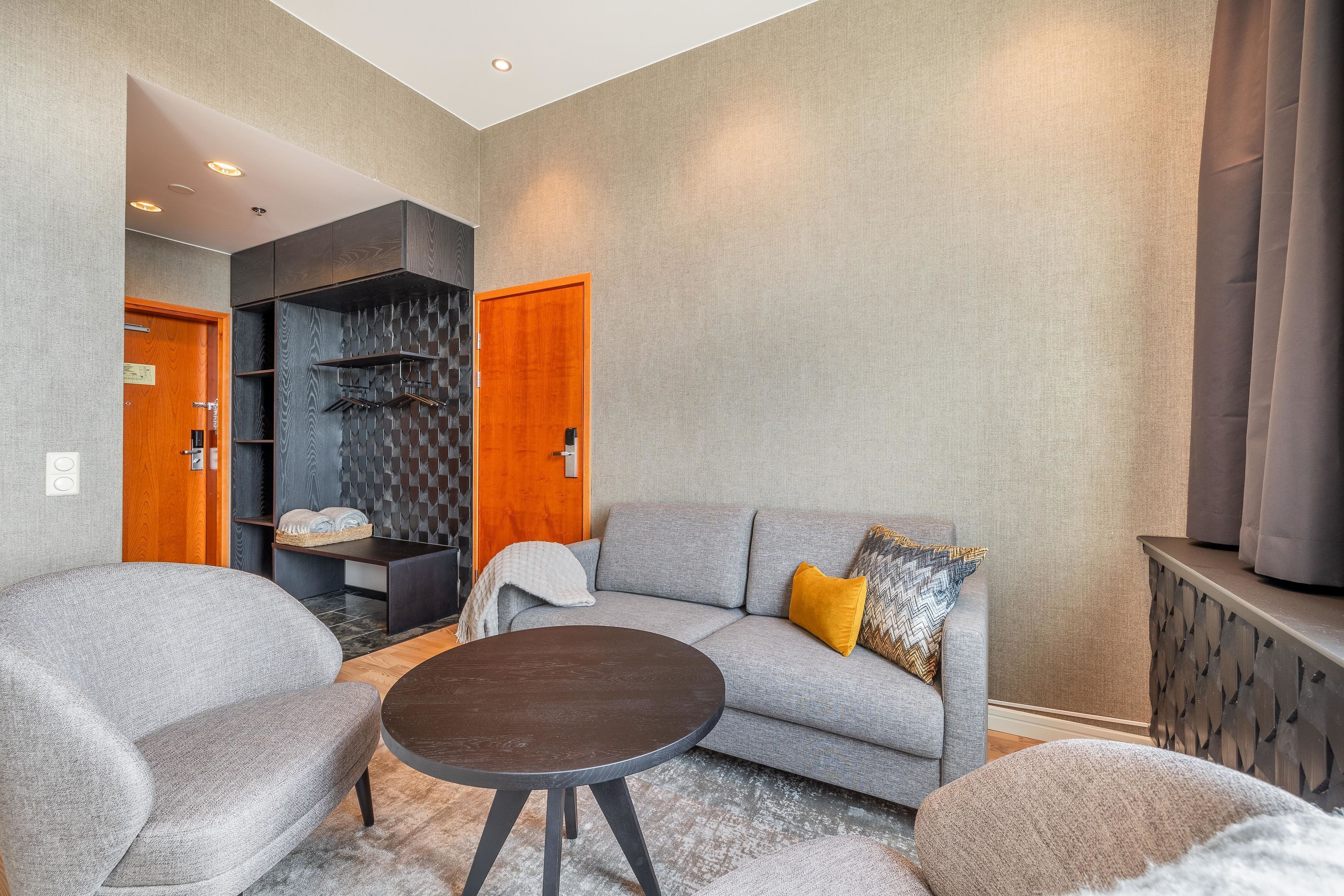 A modern living room with a grey sofa, a round coffee table, and a built-in shelving unit.