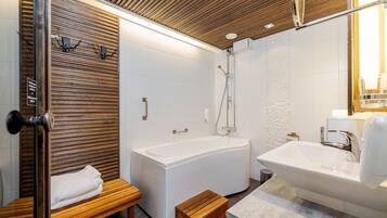 Un baño moderno con una banca de madera, una bañera y un lavamanos.