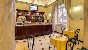 A bar area with a counter, shelves of bottles, a television, and a window with curtains. There are tables and chairs around the bar. - Hotel Cambridge (Rome)